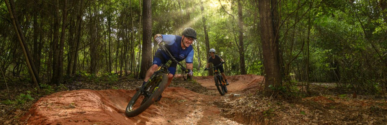 Guided Bogue Chitto mountain bike tour with Brooks Bike Shop — riders carving a berm on the state park trails